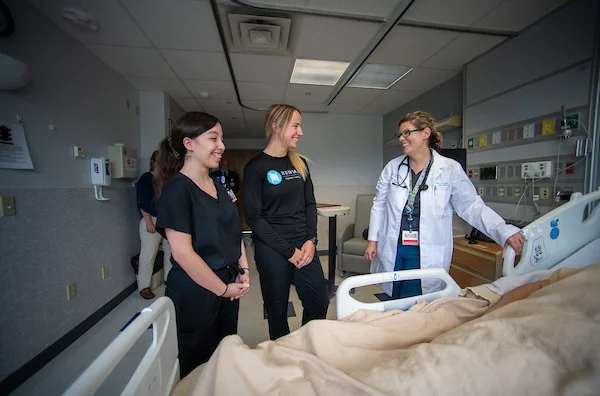 Two students and one doctor looking at a hospital bed