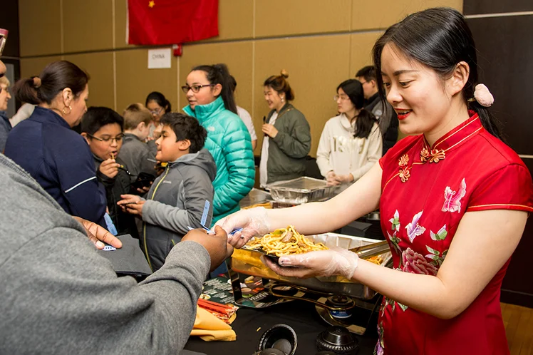 An International student at Emporia State University serves a noodle dish to a customer.