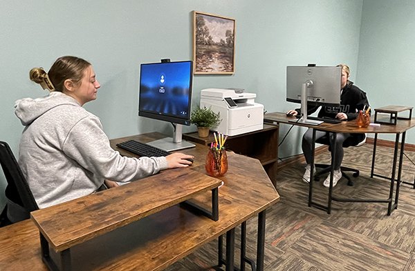 Two young women is at workstations with computers