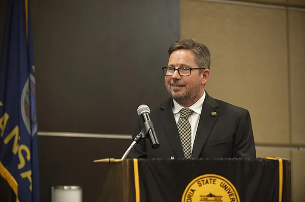 Man with beard and glasses speaks at podium