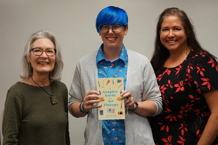 Three women with one holding a book